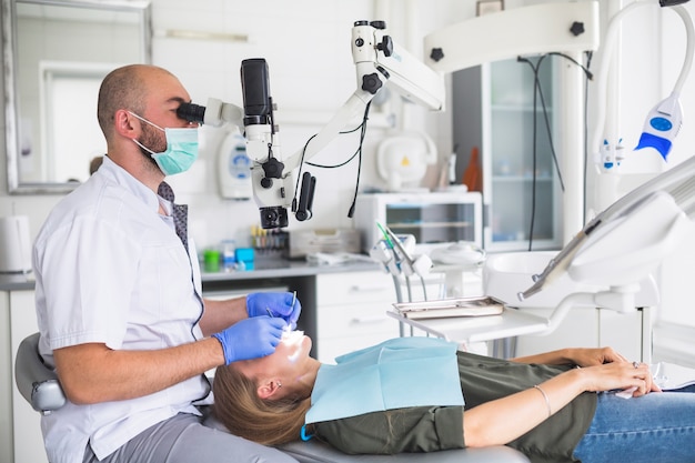 Foto tandarts die de tanden van de patiënt met tandmicroscoop onderzoekt