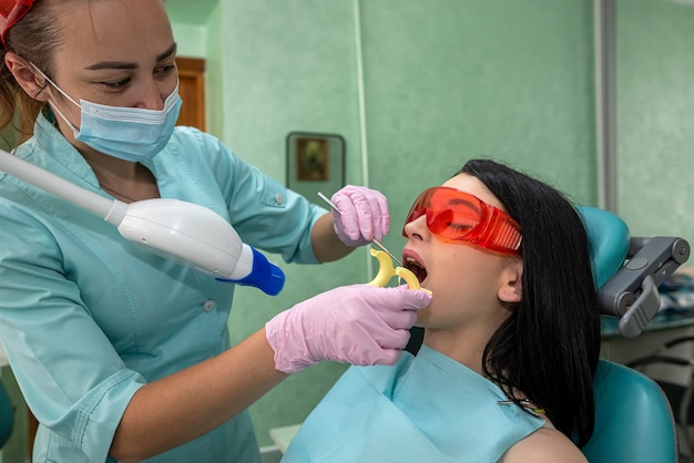 Tandarts die de tanden van de patiënt onderzoekt met een uv-lamp van dichtbij