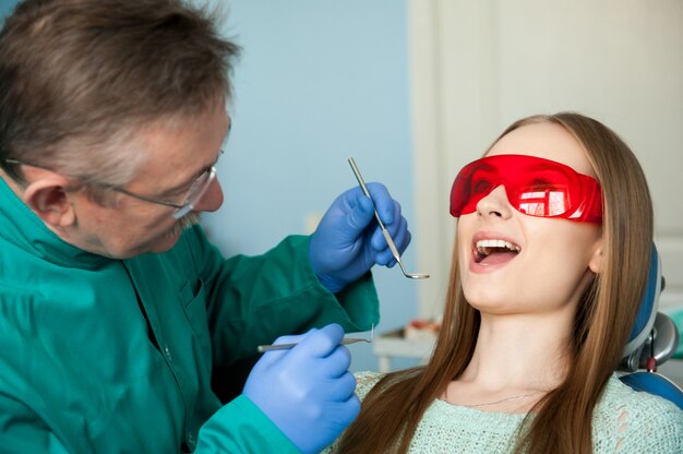 Tandarts die de tanden van een patiënt in de tandkliniek onderzoeken.