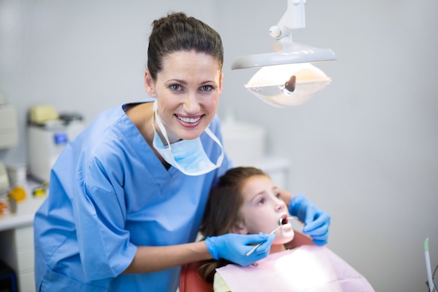 Tandarts die een jonge patiënt met hulpmiddelen in tandkliniek onderzoekt