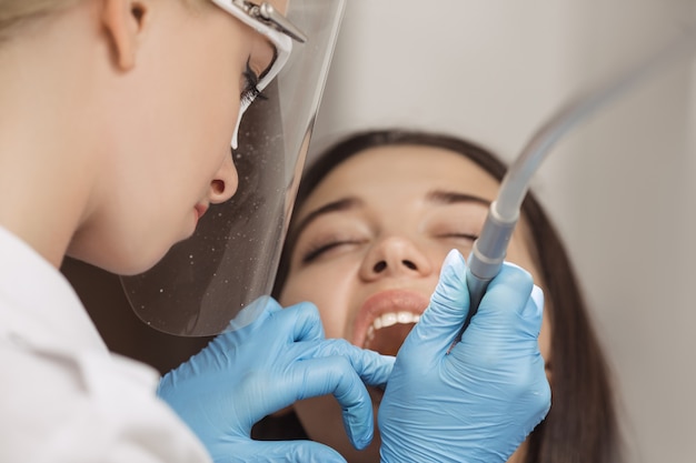 Tandarts doet een tandheelkundige behandeling op een vrouwelijke patiënt. Chirurgie close-up.