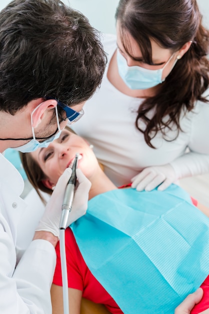 Tandarts en assistent die vrouw in kliniek behandelen