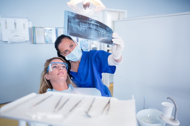 Tandarts in masker dat röntgenstraal verklaart aan patiënt