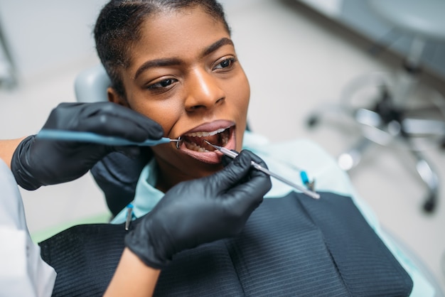 Tandarts onderzoekt de tanden van vrouwelijke patiënt in tandheelkundige kliniek.