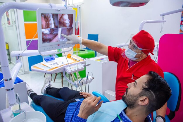 Tandarts toont aan zijn patiënt tandheelkundige beelden op een scherm in moderne tandartspraktijk
