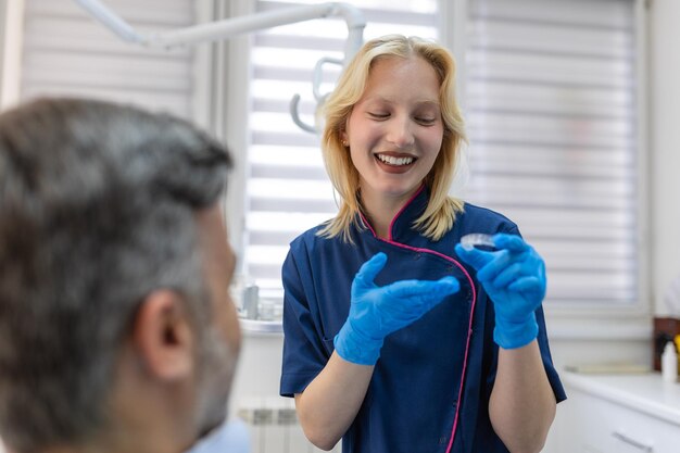 Tandarts toont onzichtbare beugels aligner Tandheelkundig consult in een orthodontische kliniek Orthodontische verwijderbare stijltangen in tandartspraktijk Tandheelkundig behandelingsconcept