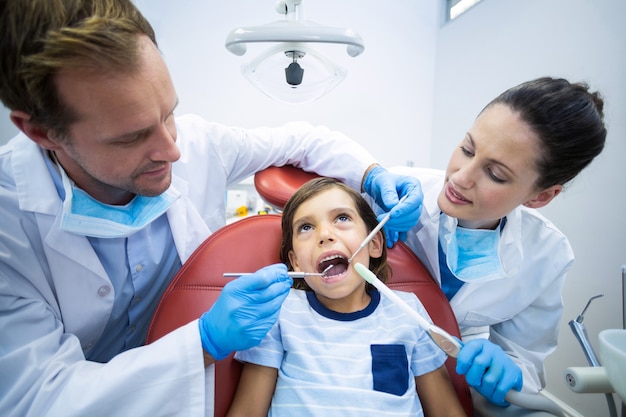 Tandartsen die jonge patiënt in tandkliniek onderzoeken