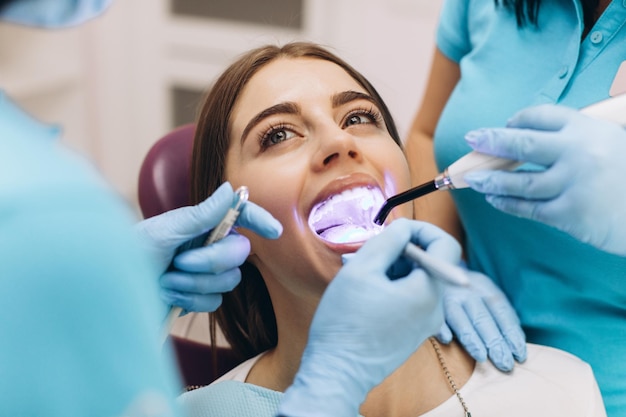 Tandartsen geven het meisje ultraviolette tanden bleken in een tandheelkundige kliniek