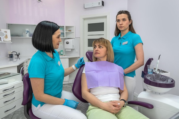 Tandartsvrouw die met haar patiënt praat over de behandeling van haar tanden