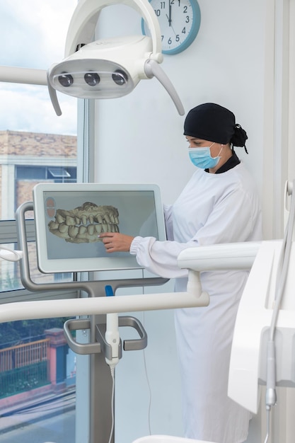 Tandartsvrouw naast een scherm met een 3D-tandmodel Tandkliniekconcept