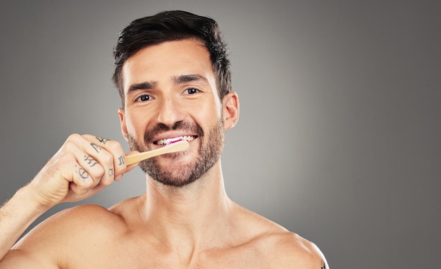 Tanden poetsen bamboe en man in studio voor tandheelkundige tandarts en mond wellness met productpromotie op mockup ruimte Modelportret met hout en milieuvriendelijke tandenborstel voor mint frisse adem