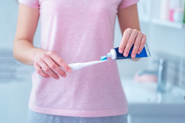 Tanden poetsen met ultrasone elektrische tandenborstel en tandpasta in de badkamer thuis