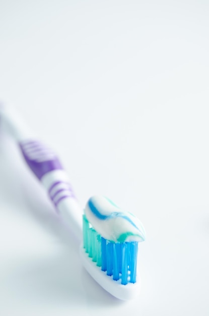 Tandenborstel en toegepaste tandpasta op witte achtergrond