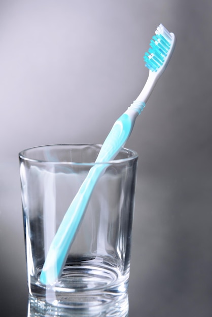 Foto tandenborstel in glas op grijze achtergrond