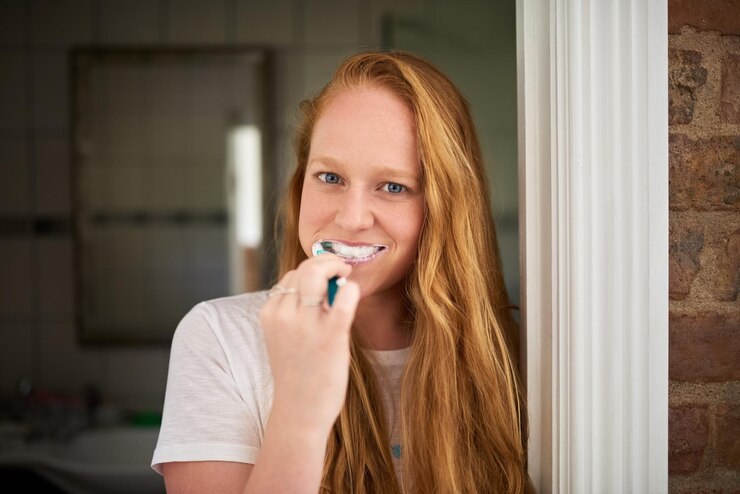 Foto tandheelkundig portret en vrouw die haar tanden poetsen in de badkamer reiniging van mond en tandvlees verzorging mondhygiëne en frisse adem met tandpasta tandenborstel en routine voor wellness en whitening