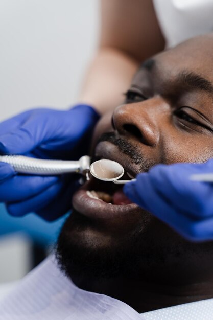 Tandheelkundige boor close-up Tandarts boren tanden van Afrikaanse man in tandheelkunde kliniek Behandeling van tanden Tandheelkundige vulling voor Afro-Amerikaanse man patiënt