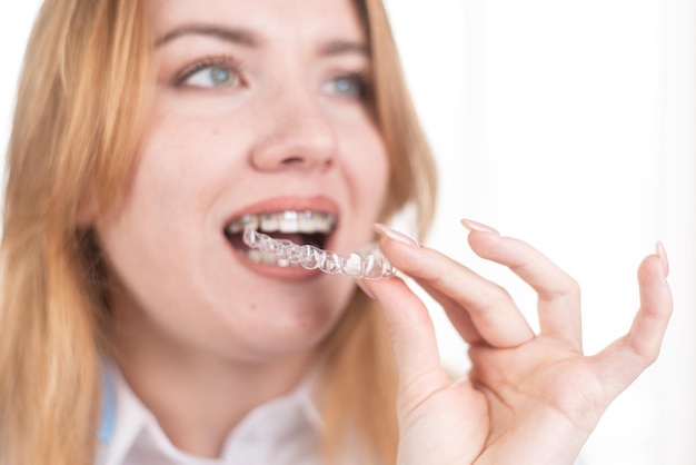 Tandheelkundige zorg Glimlachend meisje met beugels op haar tanden houdt aligners in haar handen en laat het verschil tussen hen zien