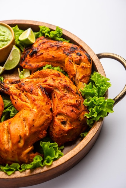 Tandoori chicken is a chicken dish prepared by roasting chicken marinated in yogurt and spices in a tandoor or a clay oven, served with onion and green chutney