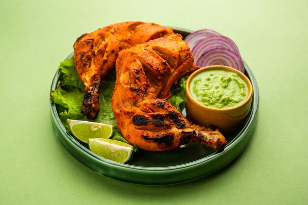 Tandoori chicken is a chicken dish prepared by roasting chicken marinated in yogurt and spices in a tandoor or a clay oven, served with onion and green chutney