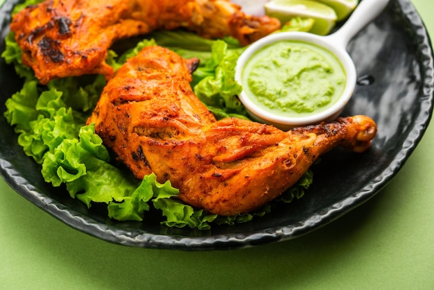 Tandoori chicken is a chicken dish prepared by roasting chicken marinated in yogurt and spices in a tandoor or a clay oven, served with onion and green chutney