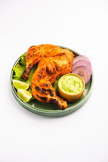 Tandoori chicken is a chicken dish prepared by roasting chicken marinated in yogurt and spices in a tandoor or a clay oven, served with onion and green chutney