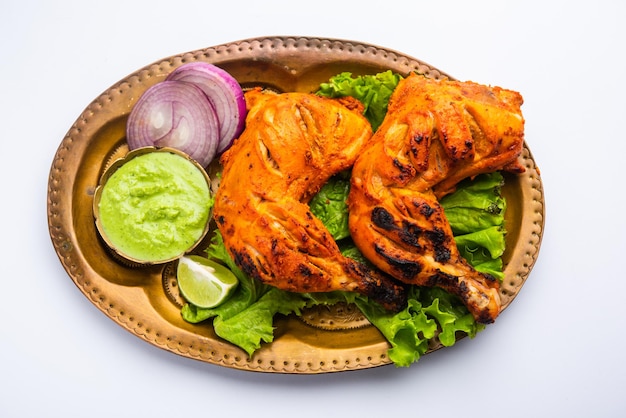 Tandoori chicken is a chicken dish prepared by roasting chicken marinated in yogurt and spices in a tandoor or a clay oven, served with onion and green chutney