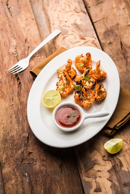 Tandoori gobi of geroosterde bloemkool tikka is een droog gerecht gemaakt door bloemkool te roosteren in de oven, tandoor. het is populair voorgerecht uit india. geserveerd met ketchup. selectieve focus