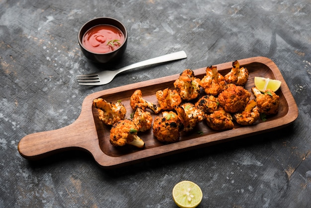Tandoori Gobi or Roasted cauliflower Tikka is a dry dish made by roasting Cauliflowers in Oven, Tandoor. It's  popular starter food from India. served with ketchup. selective focus