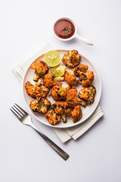 Tandoori Gobi or Roasted cauliflower Tikka is a dry dish made by roasting Cauliflowers in Oven, Tandoor. It's  popular starter food from India. served with ketchup. selective focus