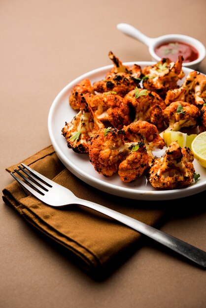 Tandoori Gobi or Roasted cauliflower Tikka is a dry dish made by roasting Cauliflowers in Oven, Tandoor. It's  popular starter food from India. served with ketchup. selective focus