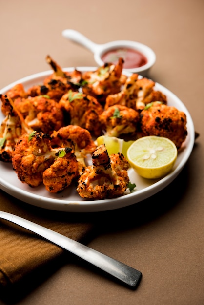 Tandoori Gobi or Roasted cauliflower Tikka is a dry dish made by roasting Cauliflowers in Oven, Tandoor. It's  popular starter food from India. served with ketchup. selective focus