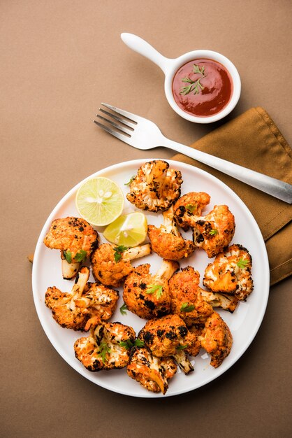 Tandoori Gobi or Roasted cauliflower Tikka is a dry dish made by roasting Cauliflowers in Oven, Tandoor. It's  popular starter food from India. served with ketchup. selective focus