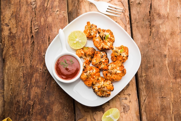 Tandoori Gobi or Roasted cauliflower Tikka is a dry dish made by roasting Cauliflowers in Oven, Tandoor. It's  popular starter food from India. served with ketchup. selective focus