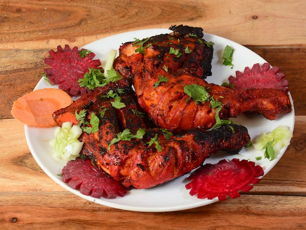 Tandoori kip bereid door het roosteren van kip gemarineerd in yoghurt en kruiden in een tandoor geserveerd op een houten rustieke achtergrond selectieve focus