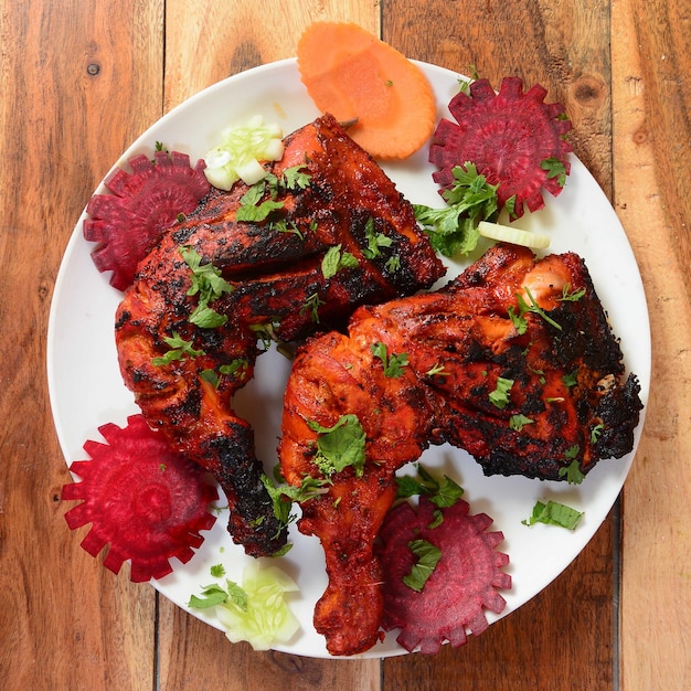 Tandoori kip bereid door het roosteren van kip gemarineerd in yoghurt en kruiden in een tandoor geserveerd op een houten rustieke achtergrond selectieve focus