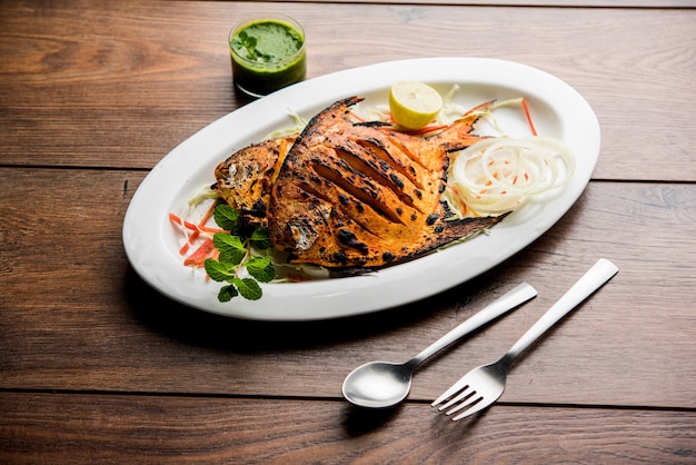 Tandoori Pomfret-vis gekookt in een klei-oven en gegarneerd met citroen, munt, kool en wortelsalade. Selectieve focus