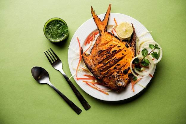 Tandoori pomfret vis gekookt in een klei-oven en gegarneerd met citroen, munt, kool en wortelsalade