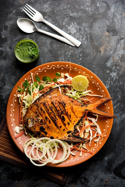 Tandoori Pomfret vis gekookt in een klei-oven en gegarneerd met citroen, munt, kool en wortelsalade