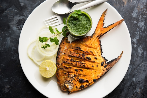 Tandoori Pomfret vis gekookt in een klei-oven en gegarneerd met citroen, munt, kool en wortelsalade