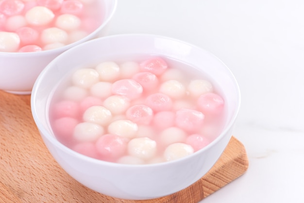 Tang yuan, tangyuan, delicious red and white rice dumpling balls in a small bowl. Asian traditional festive food for Chinese Winter Solstice Festival, close up.