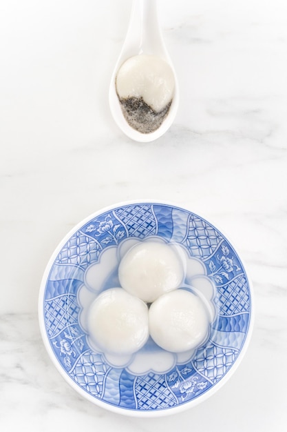 Tang yuan tangyuan yuanxiao in a small bowl stuffed with sesame\
fillings top view flat lay delicious asian food rice dumpling balls\
for festival