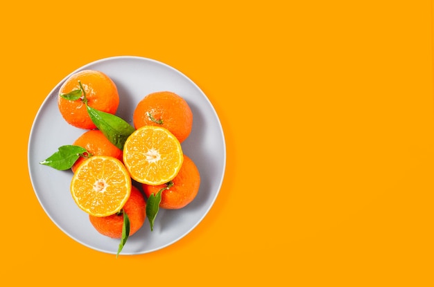 Tangerine, clementine with leaves on and a glass of orange juice with white background. Top view.