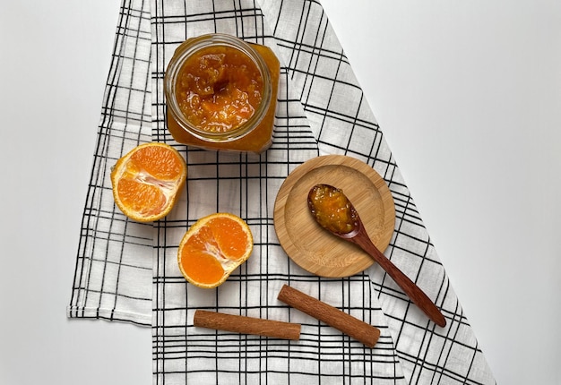 Photo tangerine jam tangerine slices cinnamon on a checkered towel light background top view