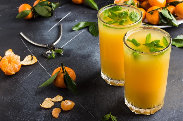 Photo tangerine juice in glasses on dark background