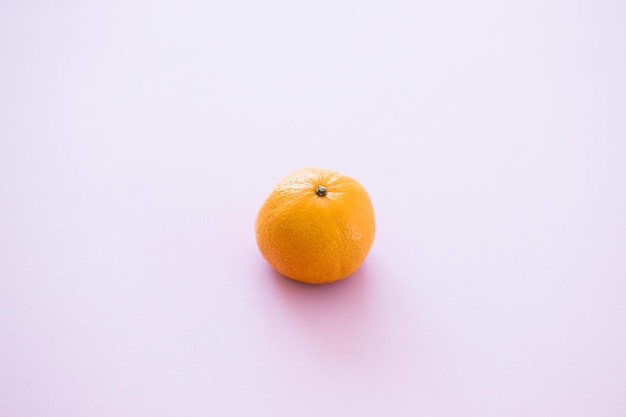 Оранжевый мандарин на розовом фоне