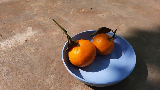 Tangerine oranges in blue bowl with exposed cement floor