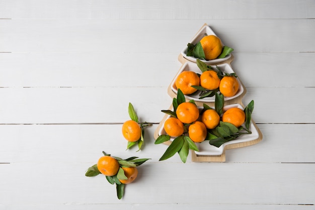 Tangerine in the shape of Christmas tree on wooden background. Christmas breacfast idea for kids.