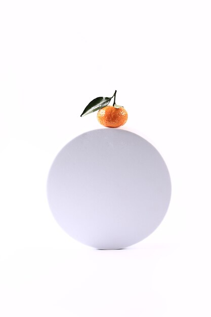 Tangerine on a white round podium soft selective focus winter festive background