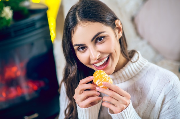 Photo tangerine. woman in white clothes eating a tangerine