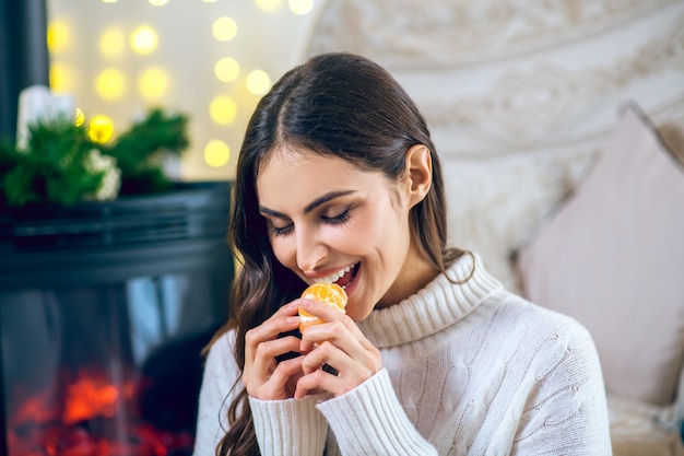 Tangerine. Woman in white clothes eating a tangerine